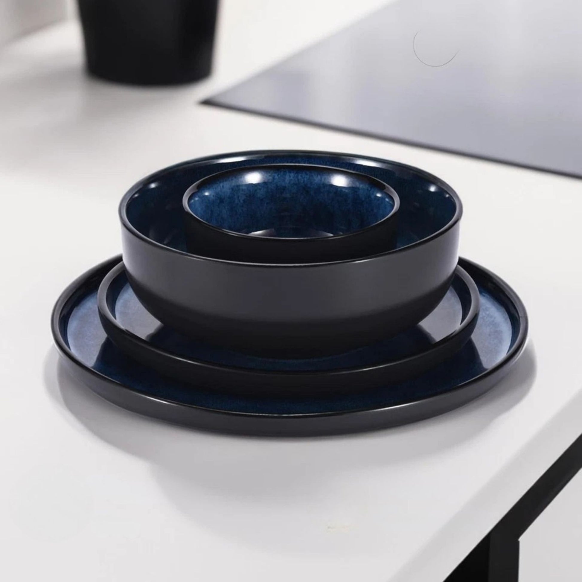 Close-up of stacked blue ceramic bowls and plates on a modern white kitchen counter.