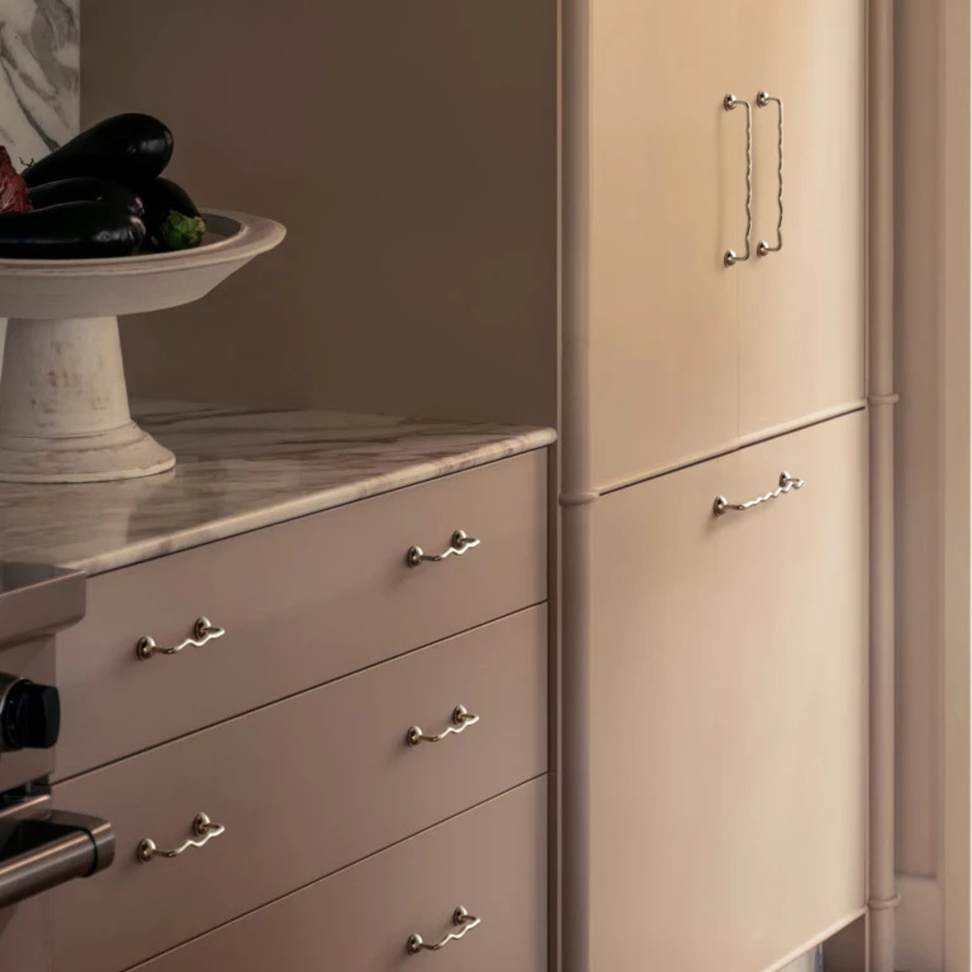 Kitchen cabinets with multiple wavy metal handles installed on drawers and doors