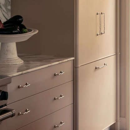 Kitchen cabinets with multiple wavy metal handles installed on drawers and doors