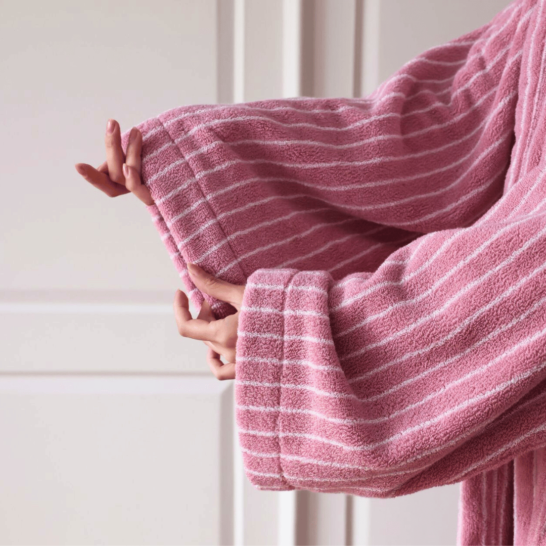 Person holding a pink and white striped towel against a neutral background