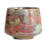 Handmade ceramic cup with textured red, green, and turquoise glaze sitting on a white tabletop.