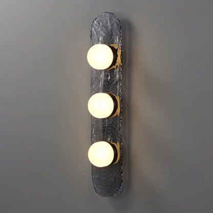 three bulb sconce with brass mount on dark raindrop textured backplate