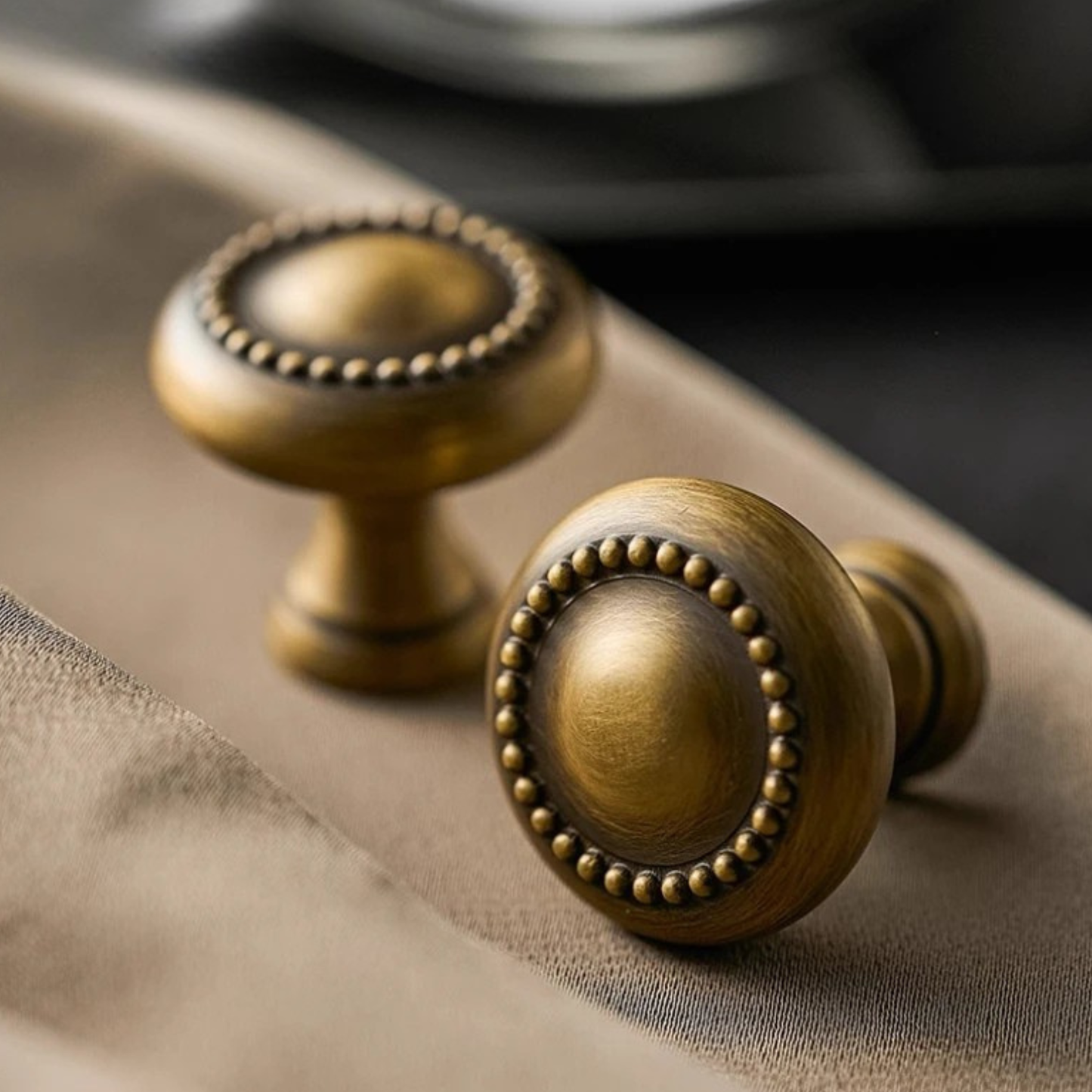 A pair of golden drawer knobs placed on a marble countertop with soft lighting.