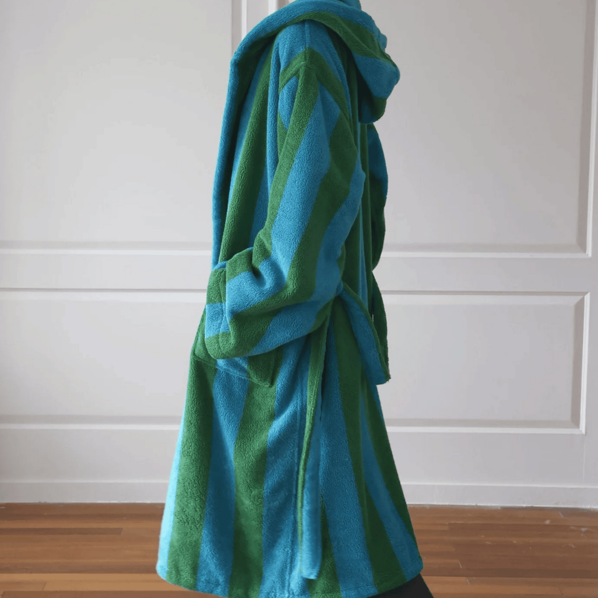 Blue and green striped robe draped over a chair against a white paneled wall.