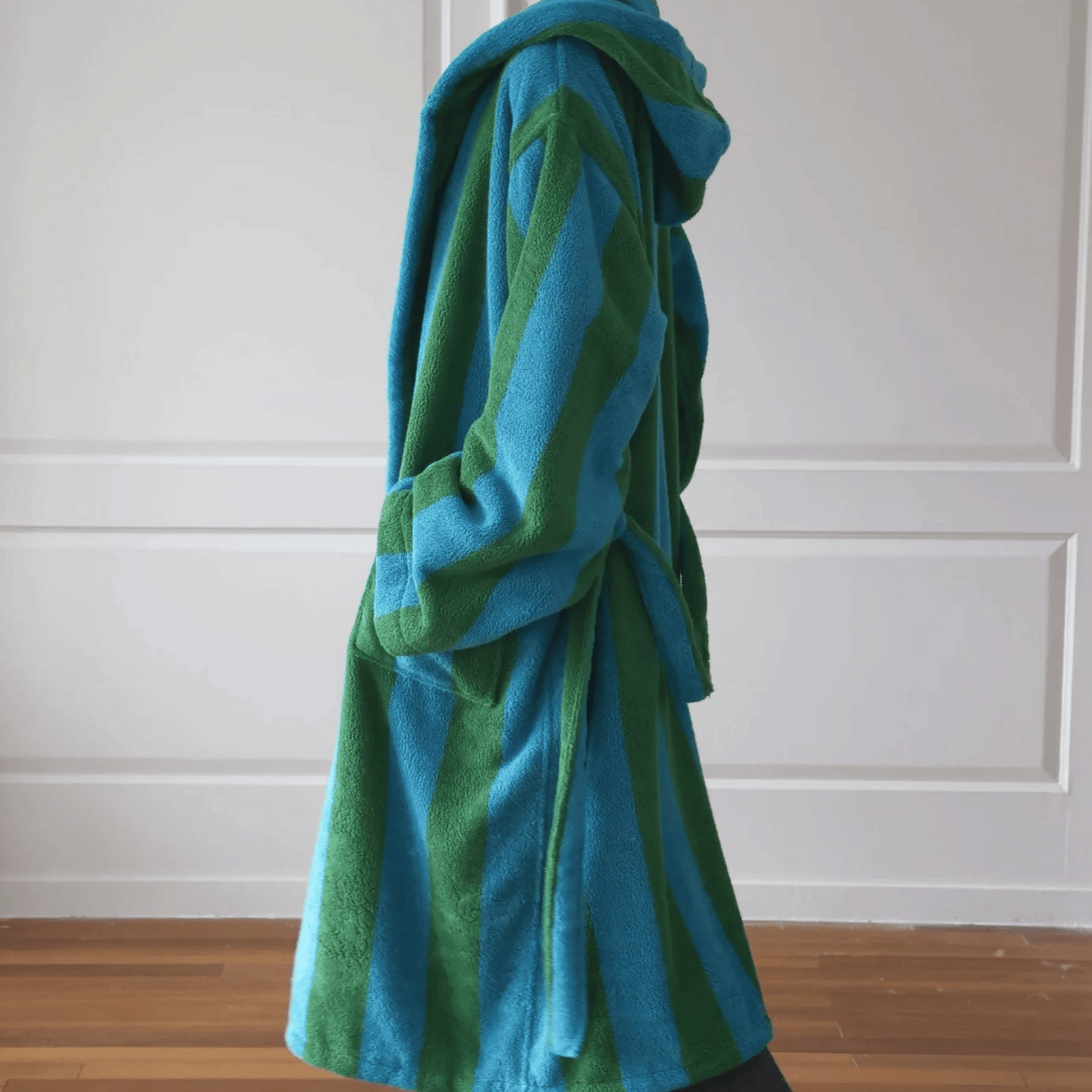 Blue and green striped robe draped over a chair against a white paneled wall.