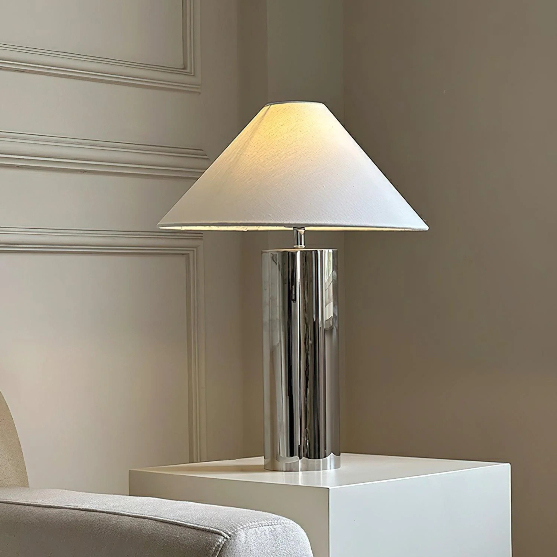 chrome table lamp with white lampshade beside a white sofa