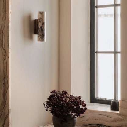 Marble wall sconce mounted near a window in a cozy, softly lit interior space.