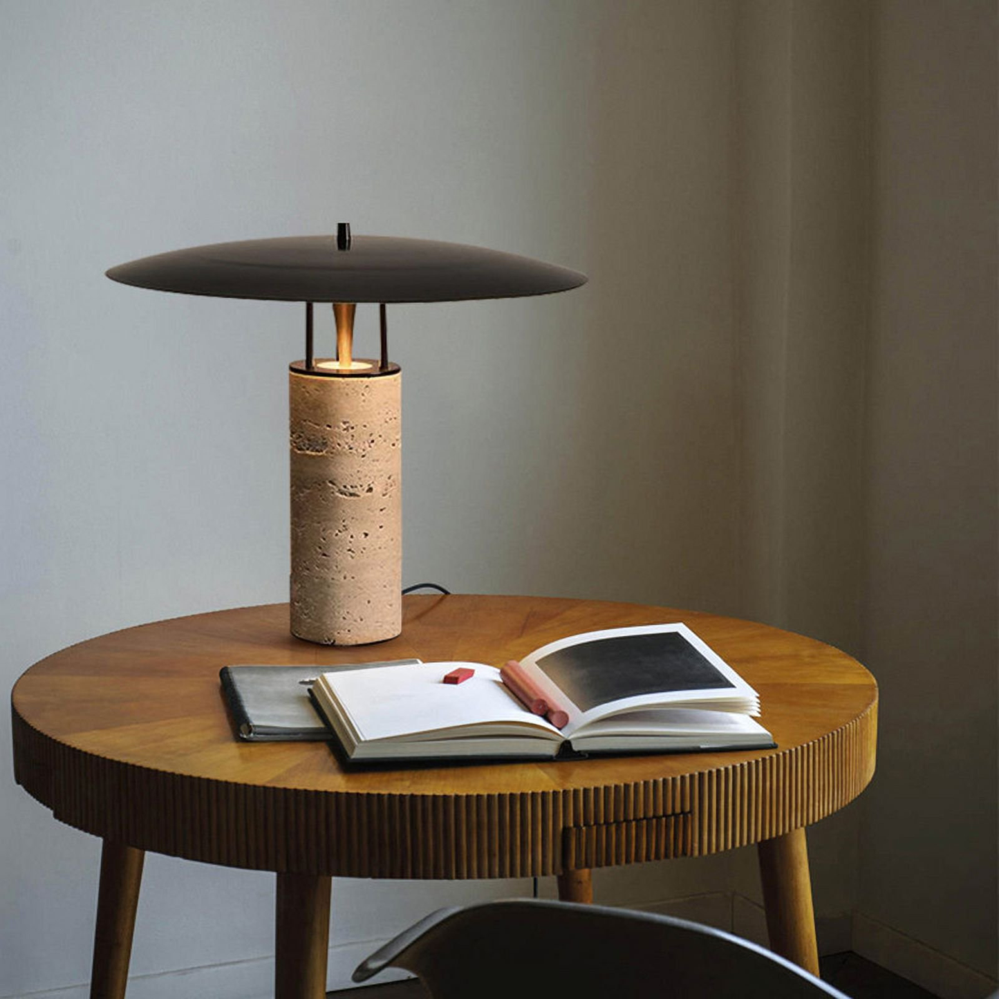 Round wooden table with a bamboo lamp next to an open book and reading glasses
