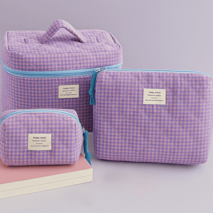 Set of purple checkered bags with blue zippers on a light gray background
