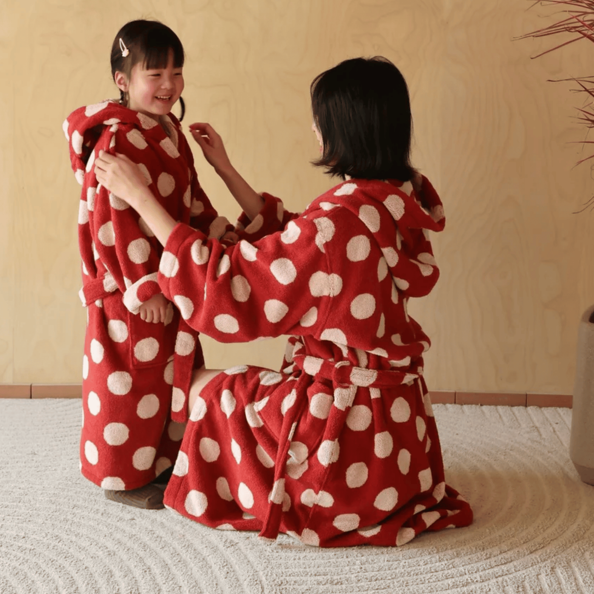 Two people wearing red polka dot robes sitting on a tatami mat.