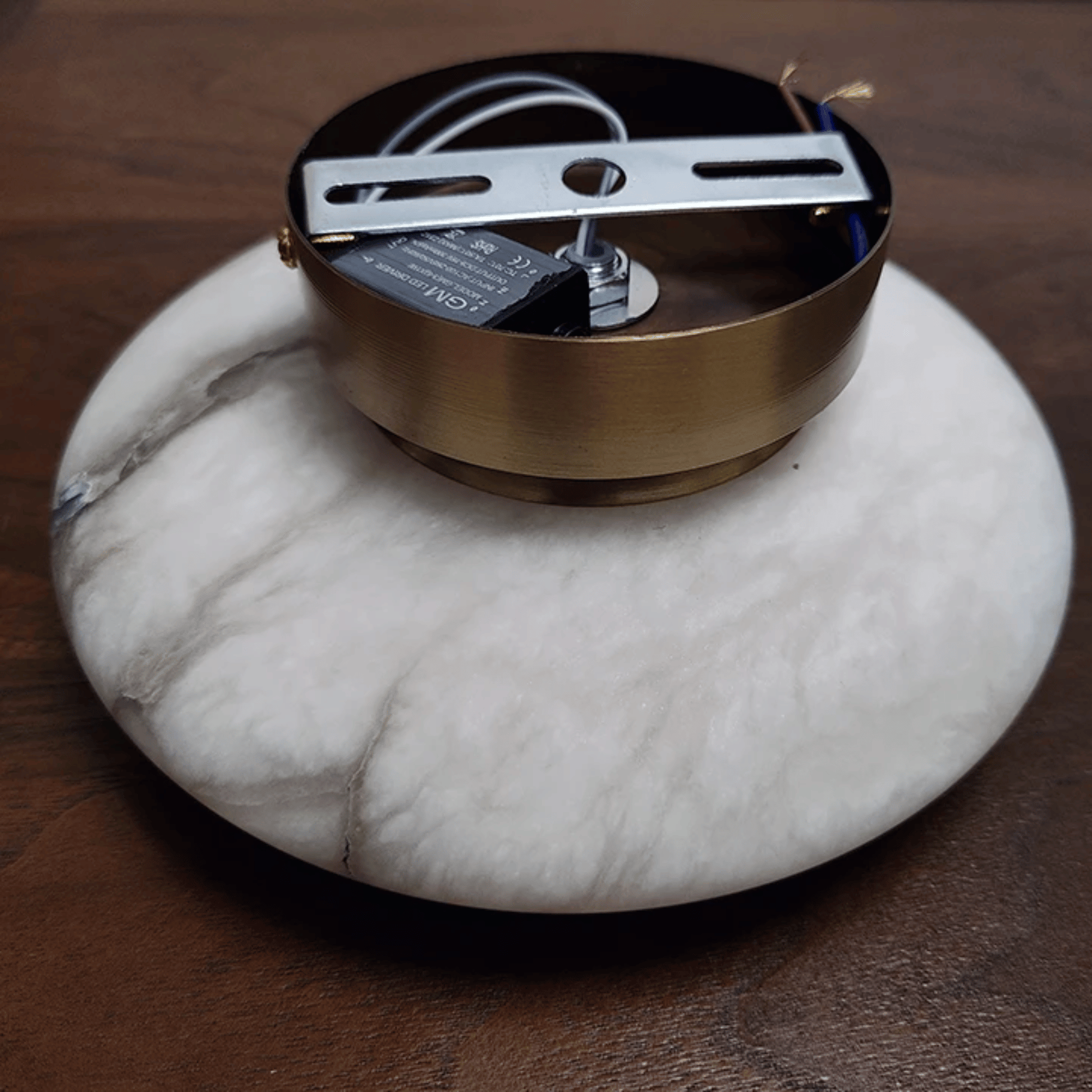 Round metallic object on a marble coaster with a wooden background