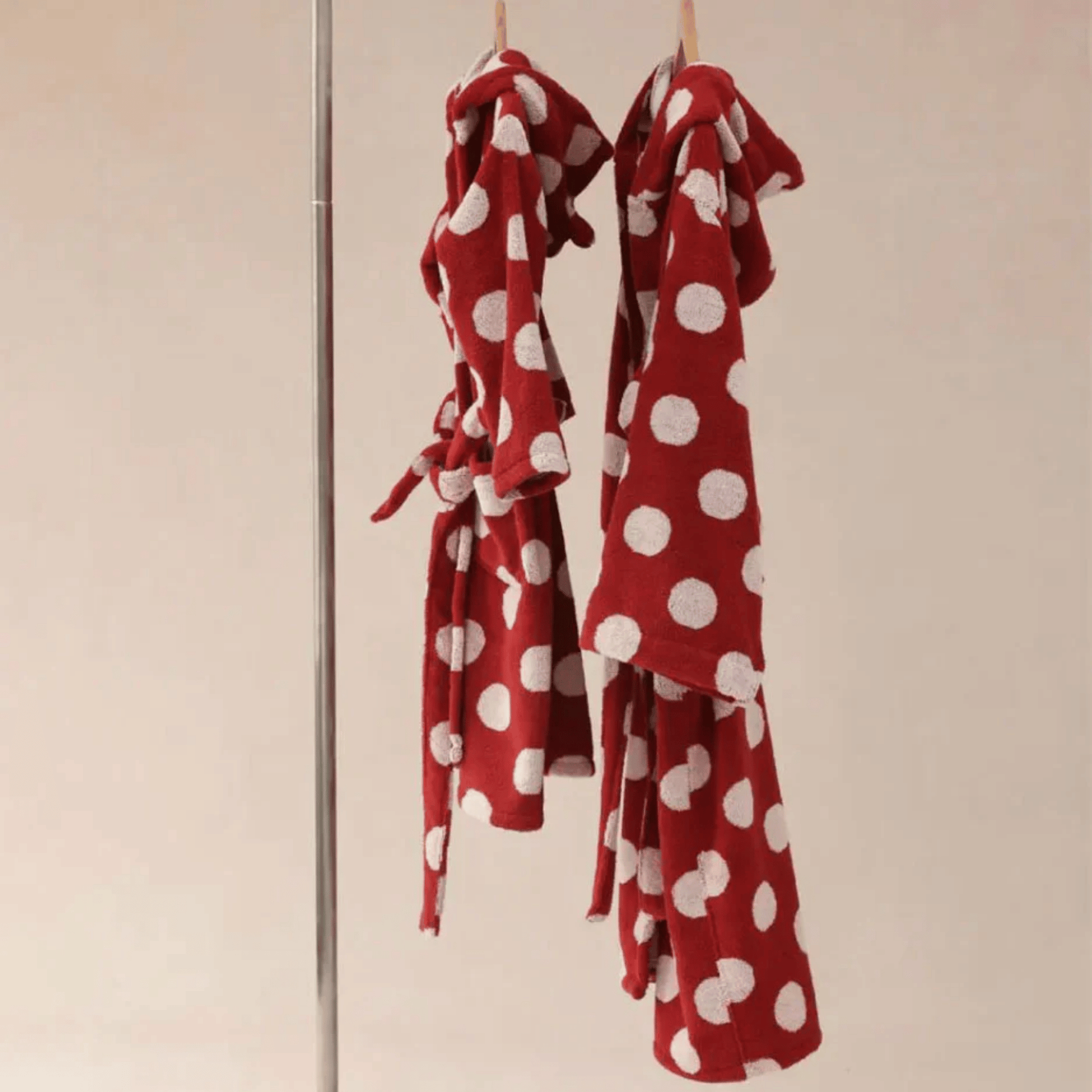 Red polka dot dress hanging on a rack against a beige wall