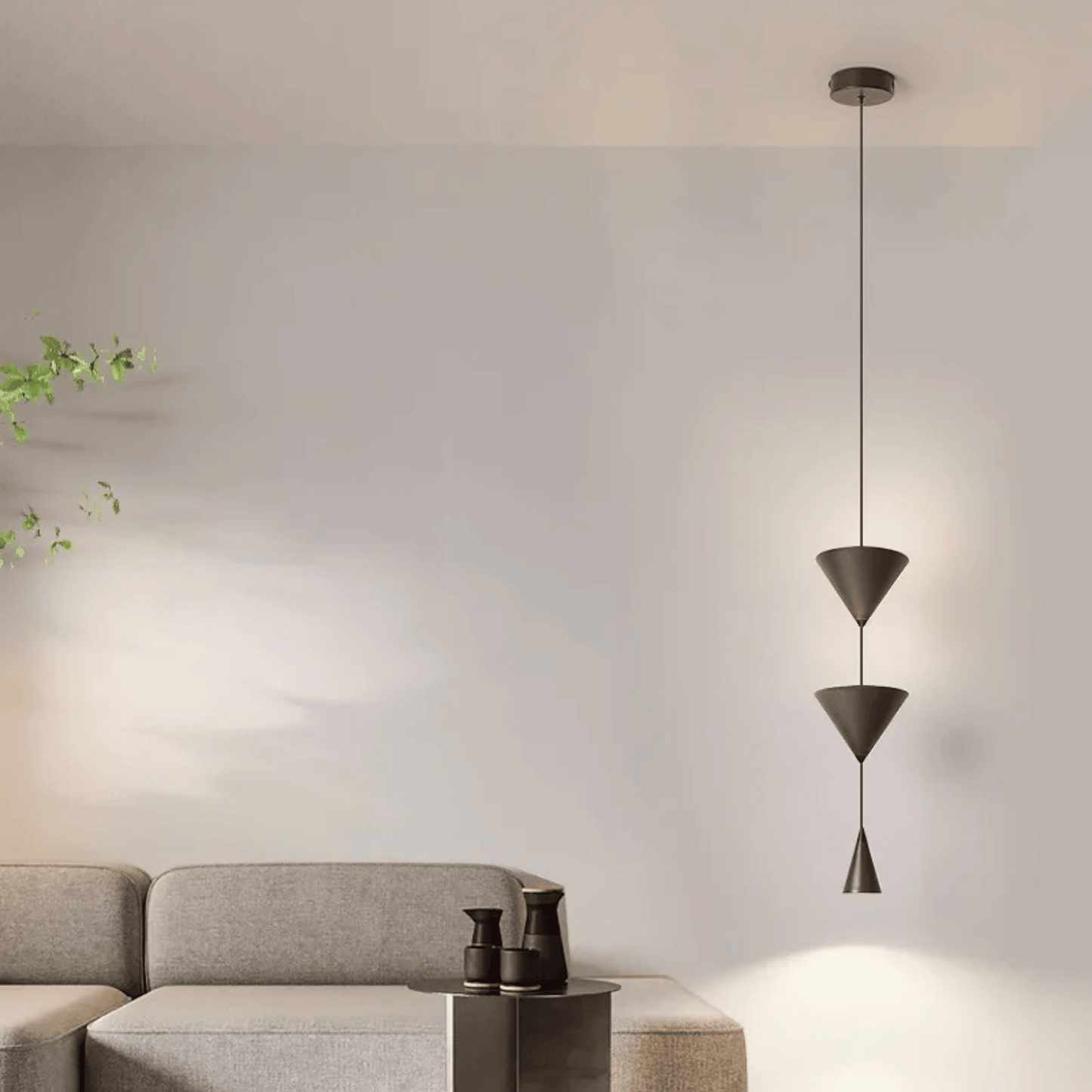 Modern pendant light hanging in a living room with a gray sofa and decorative items.