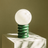 Table lamp with a white globe and green spiral base on a neutral background