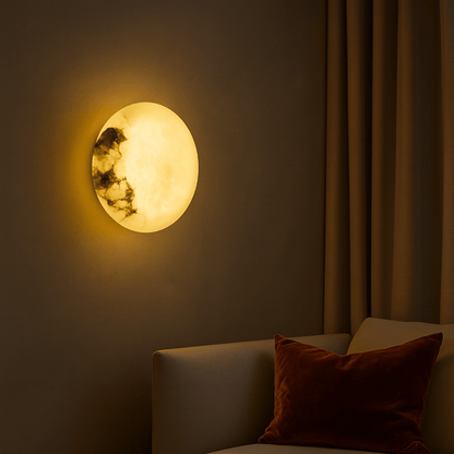Round wall light fixture on a dark wall with a sofa and pillow in the foreground