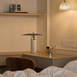 Cozy bedroom corner with a bamboo table lamp on a wooden side shelf casting warm light