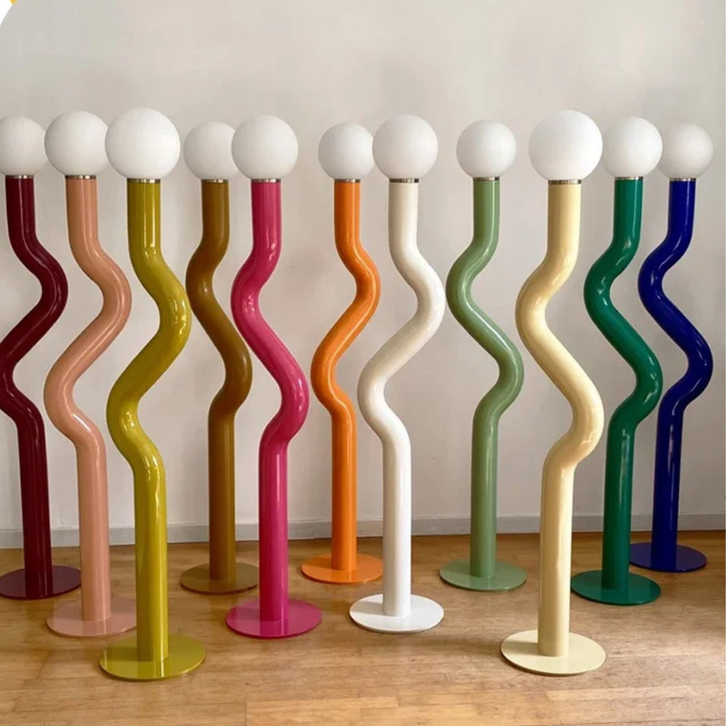 Multiple wavy floor lamps in assorted colors including orange, green, purple, and white standing together in a modern interior setup.