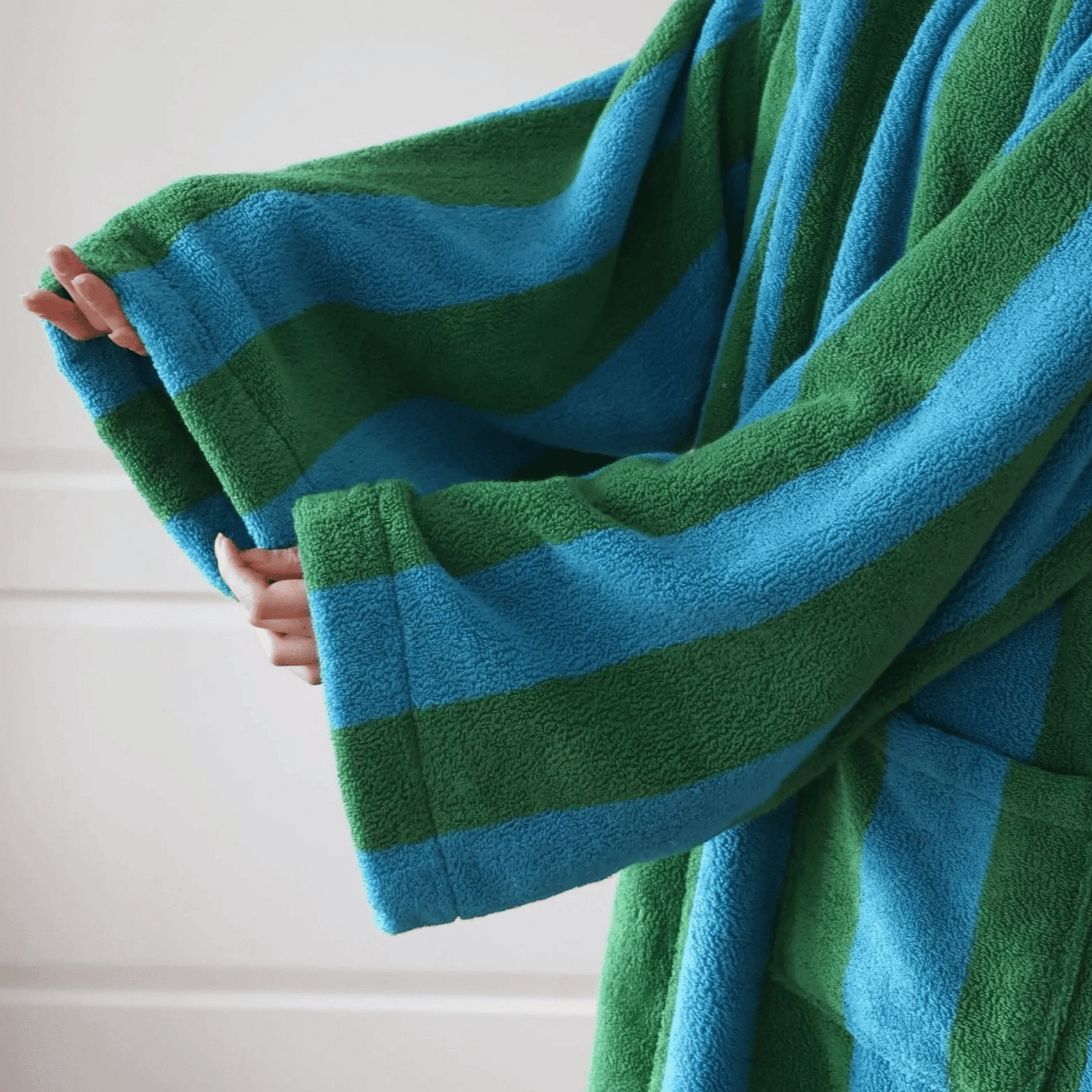 Green and blue striped towel being held against a white background
