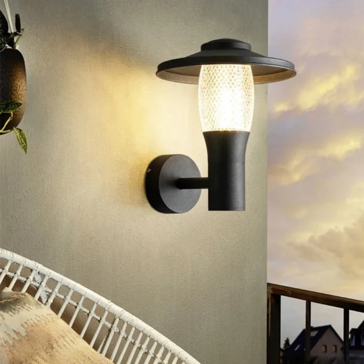 Modern outdoor wall light glowing warmly on a balcony wall at sunset