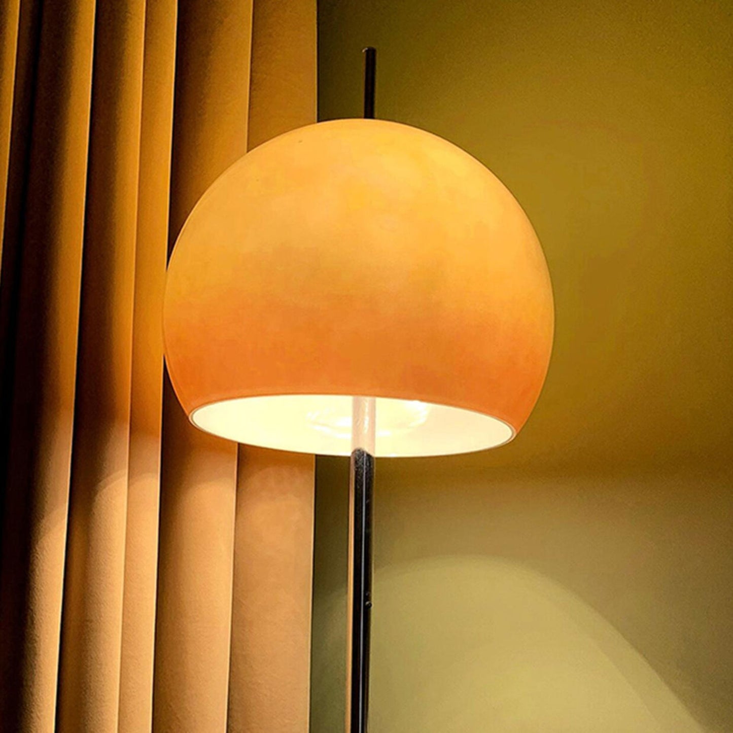 A yellow globe-shaped lamp illuminating a cozy corner near a bookshelf, with soft lighting against a red wall.
