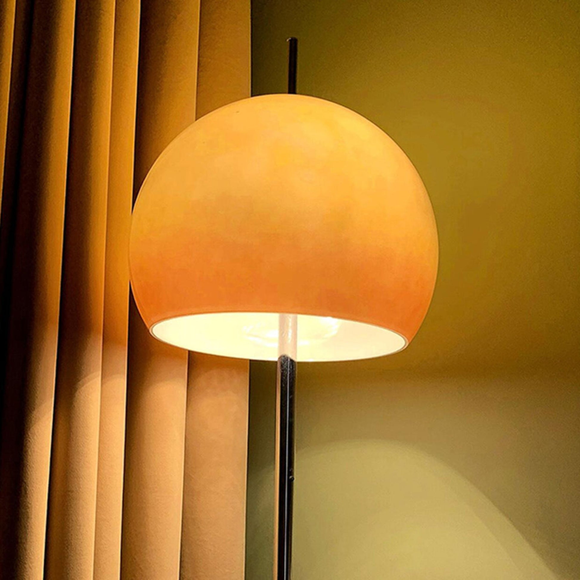 A yellow globe-shaped lamp illuminating a cozy corner near a bookshelf, with soft lighting against a red wall.