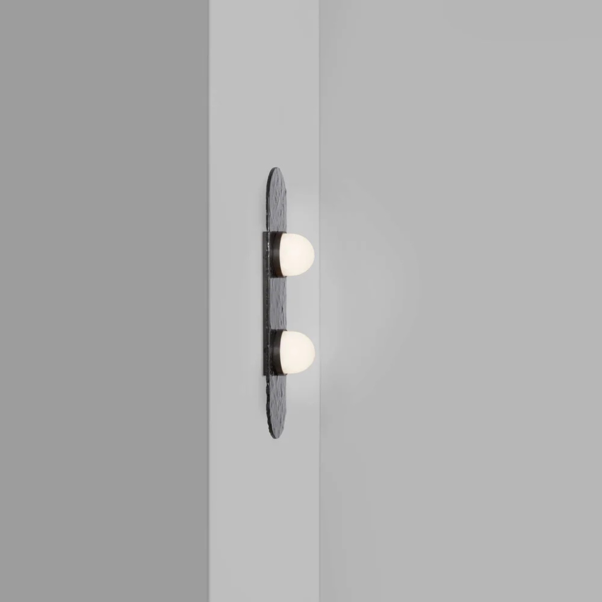 two bulb wall sconce on a grey wall with oval textured backplate
