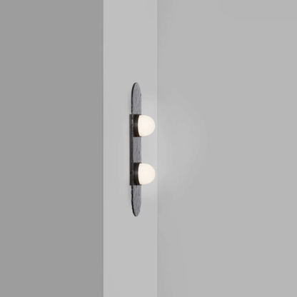 two bulb wall sconce on a grey wall with oval textured backplate