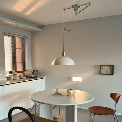 A matte white dome pendant lamp hanging from an adjustable ceiling arm over a round dining table in a contemporary kitchen.