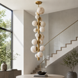 Modern chandelier hanging in a stylish interior with stairs and large windows.