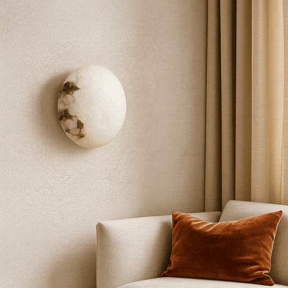Decorative wall light fixture on a beige wall with a sofa and orange pillow.