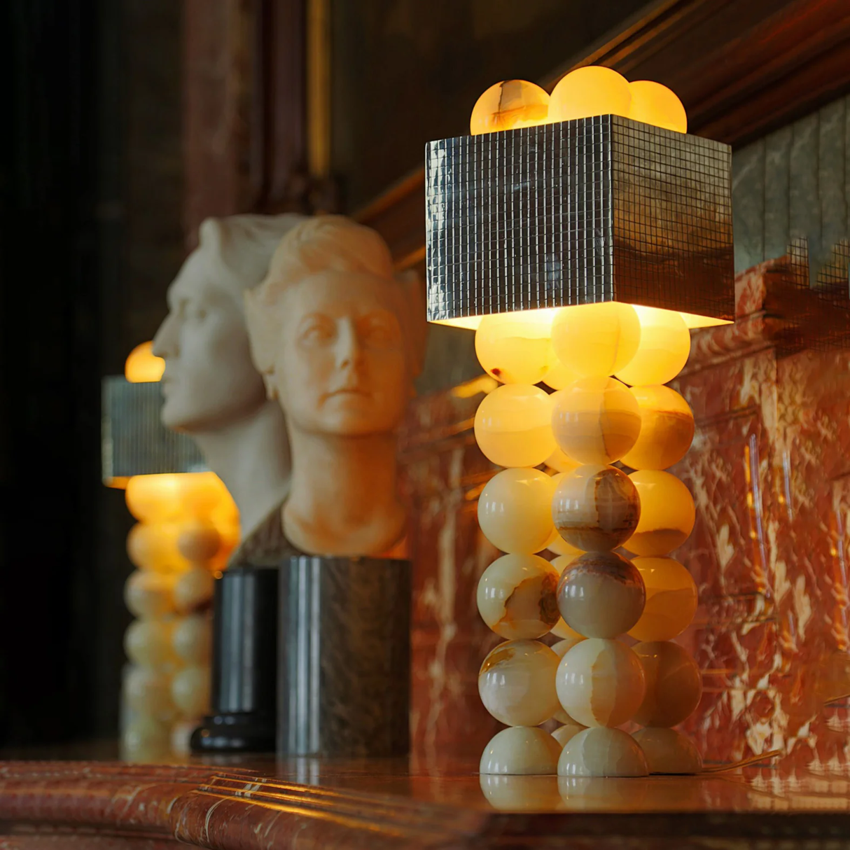 Decorative lamp with spherical design and textured square shade in a warm setting.