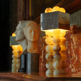 Decorative lamp with spherical design and textured square shade in a warm setting.