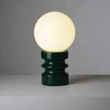 Table lamp with a green base and white bulb on a gray background