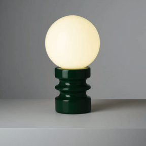 Table lamp with a green base and white bulb on a gray background