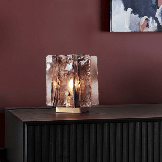 Glass table lamp with a textured design on a wooden surface and red wall background