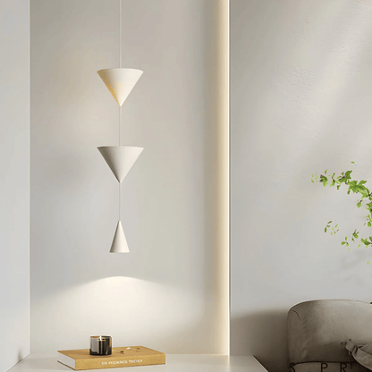 Modern pendant light fixture in a minimalistic room setting with a plant and books.