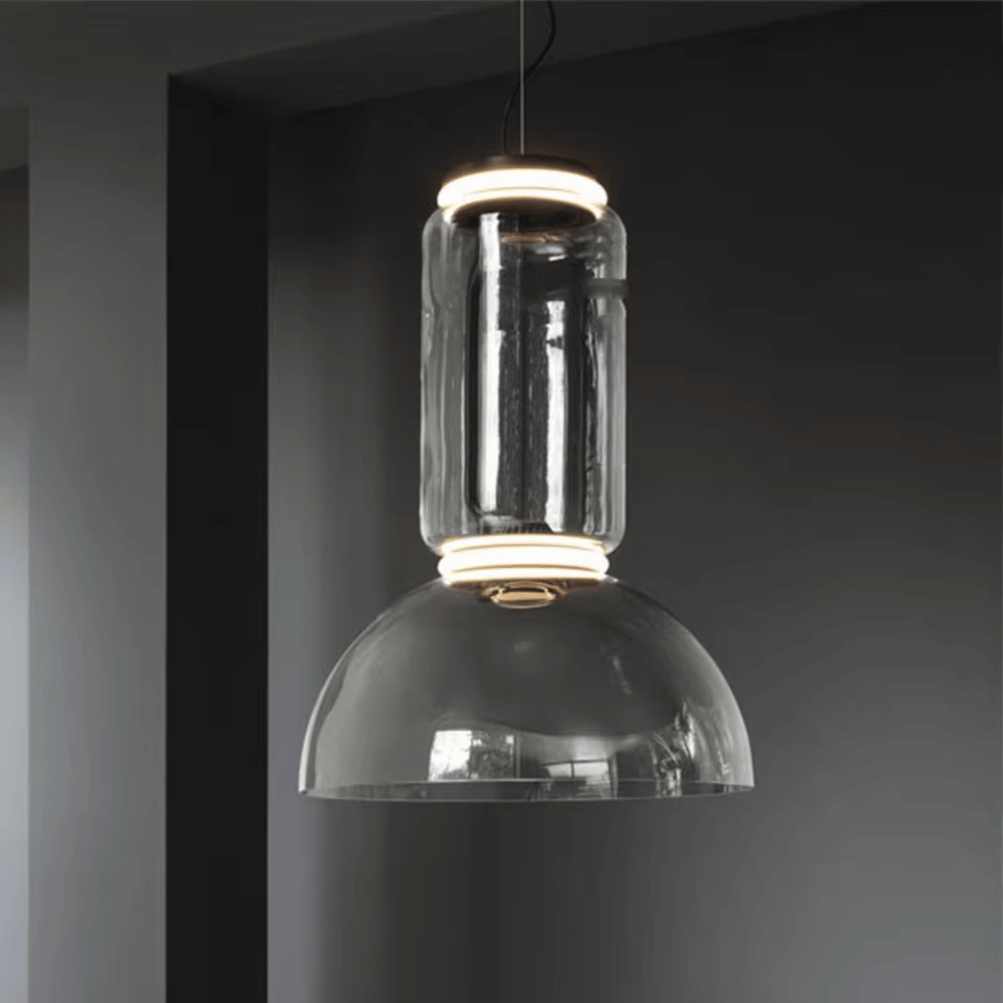 Modern pendant light with clear glass shade against a dark background