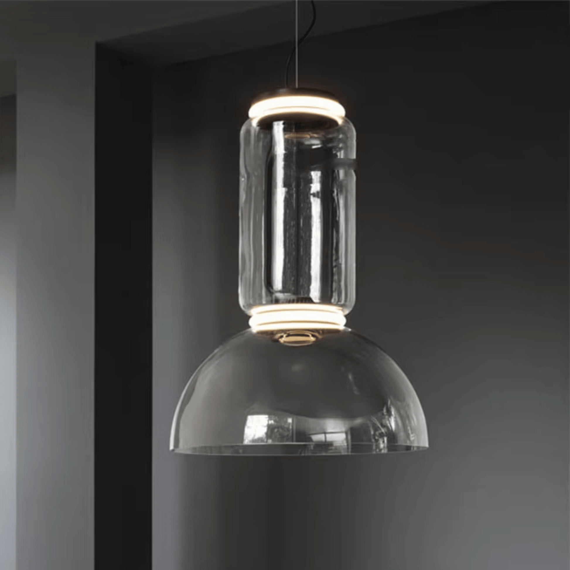 Modern pendant light with clear glass shade against a dark background