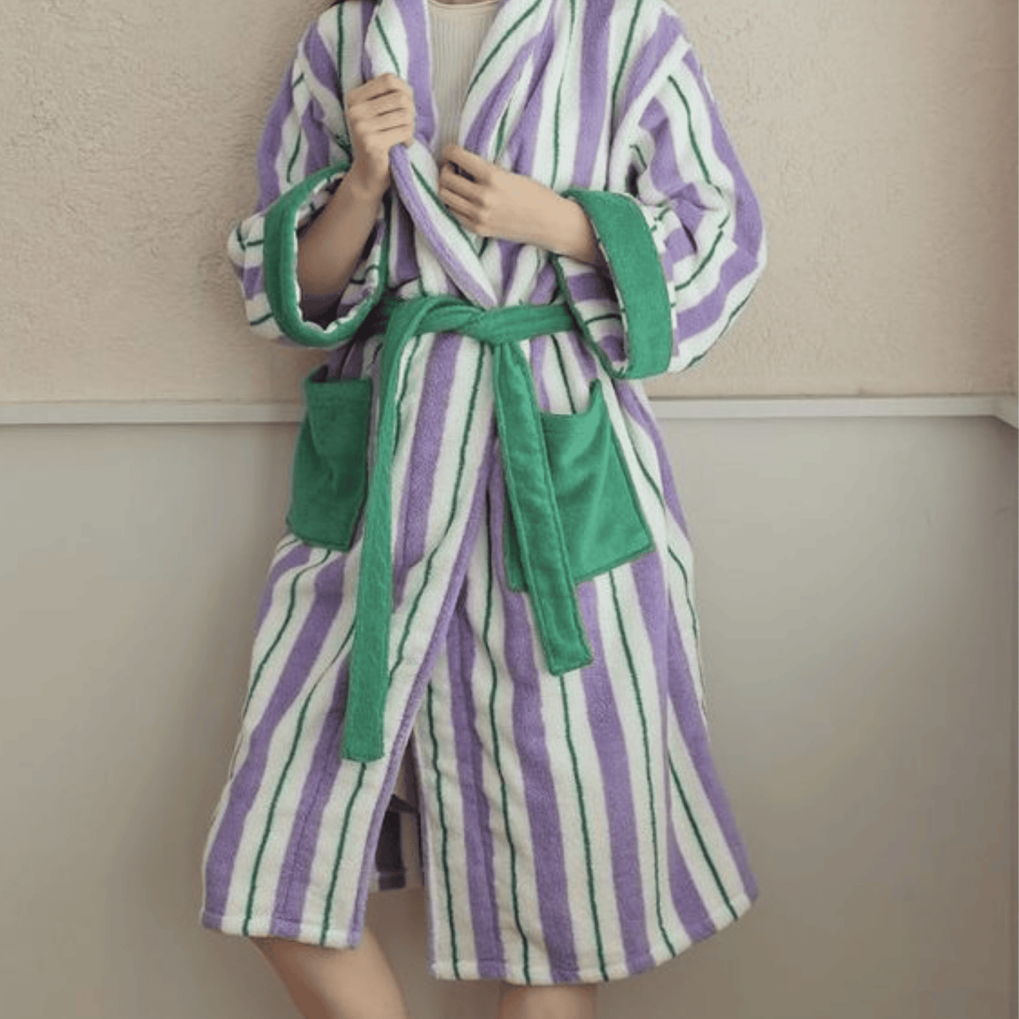 Person wearing a striped robe with green accents against a neutral background
