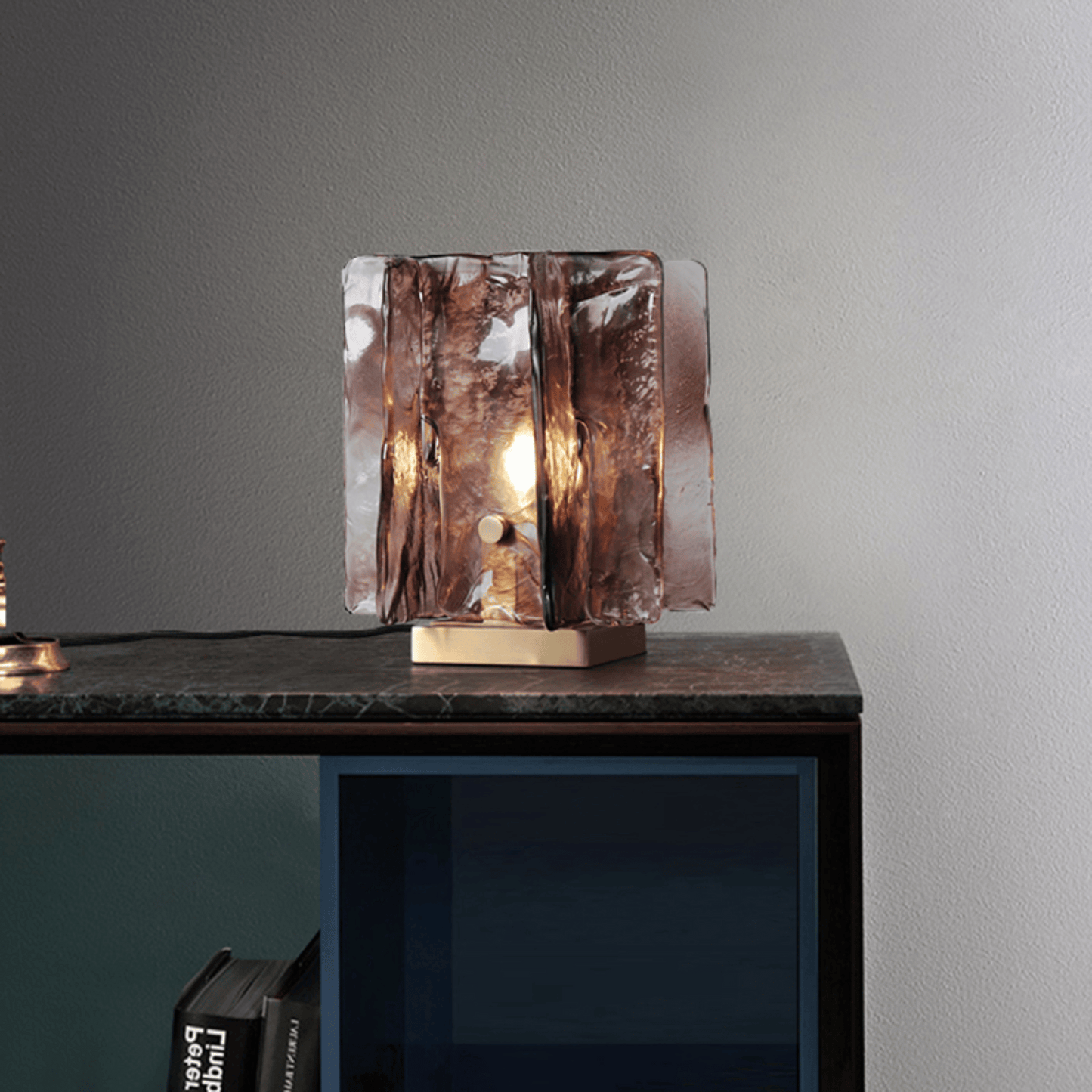 Glass table lamp with a textured design on a marblesurface and concrete wall background