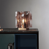 Glass table lamp with a textured design on a marblesurface and concrete wall background