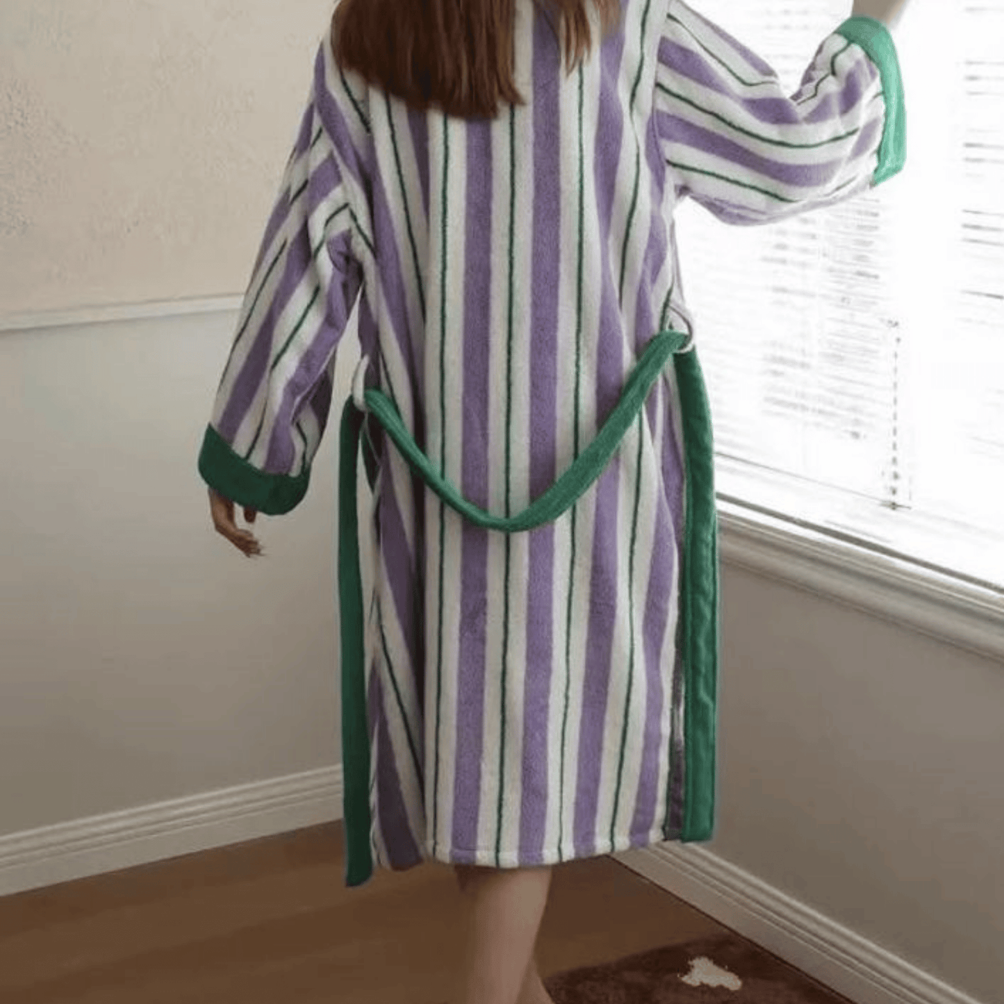 Person wearing a striped robe with green trim in a room.