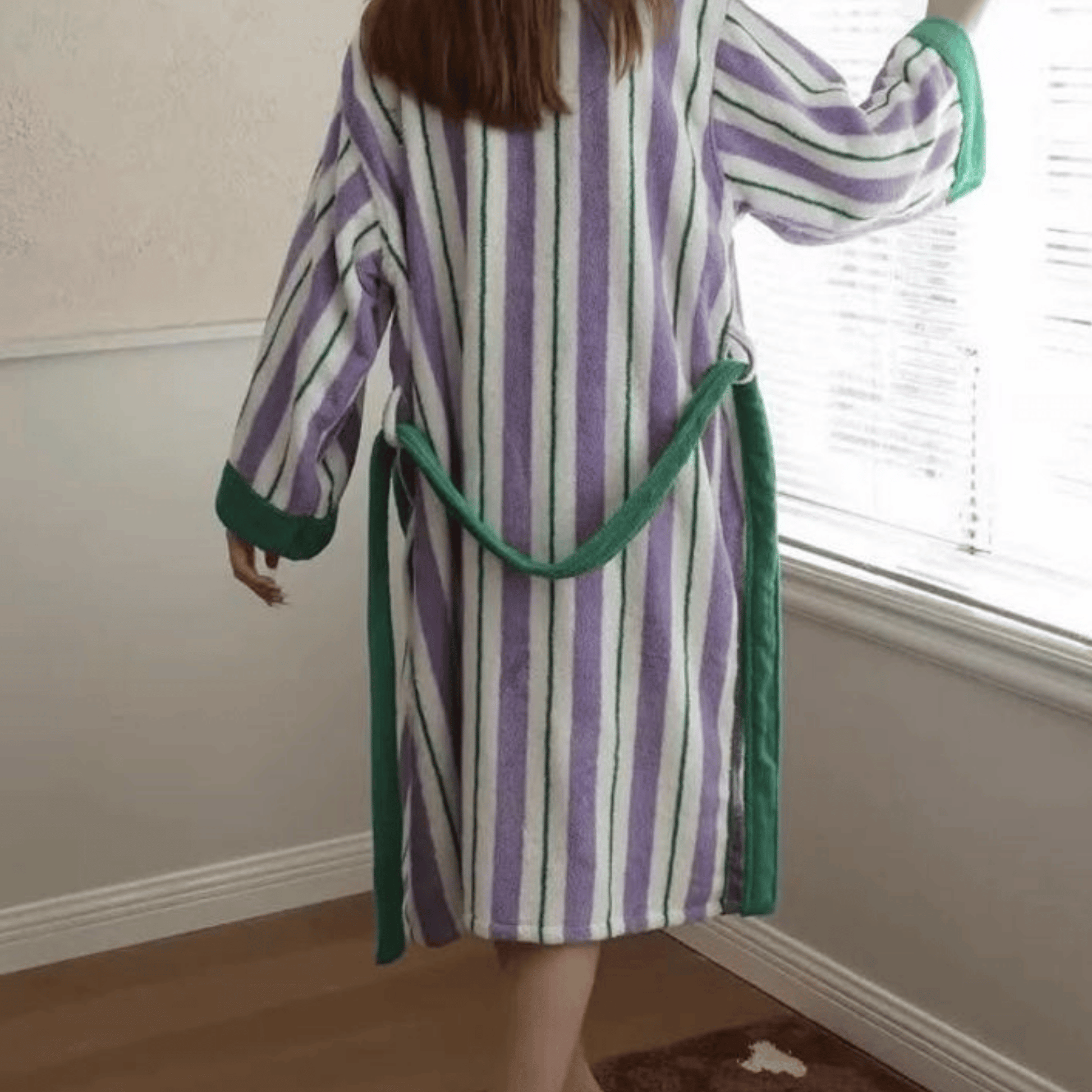 Person wearing a striped robe with green trim in a room.