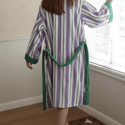 Person wearing a striped robe with green trim in a room.