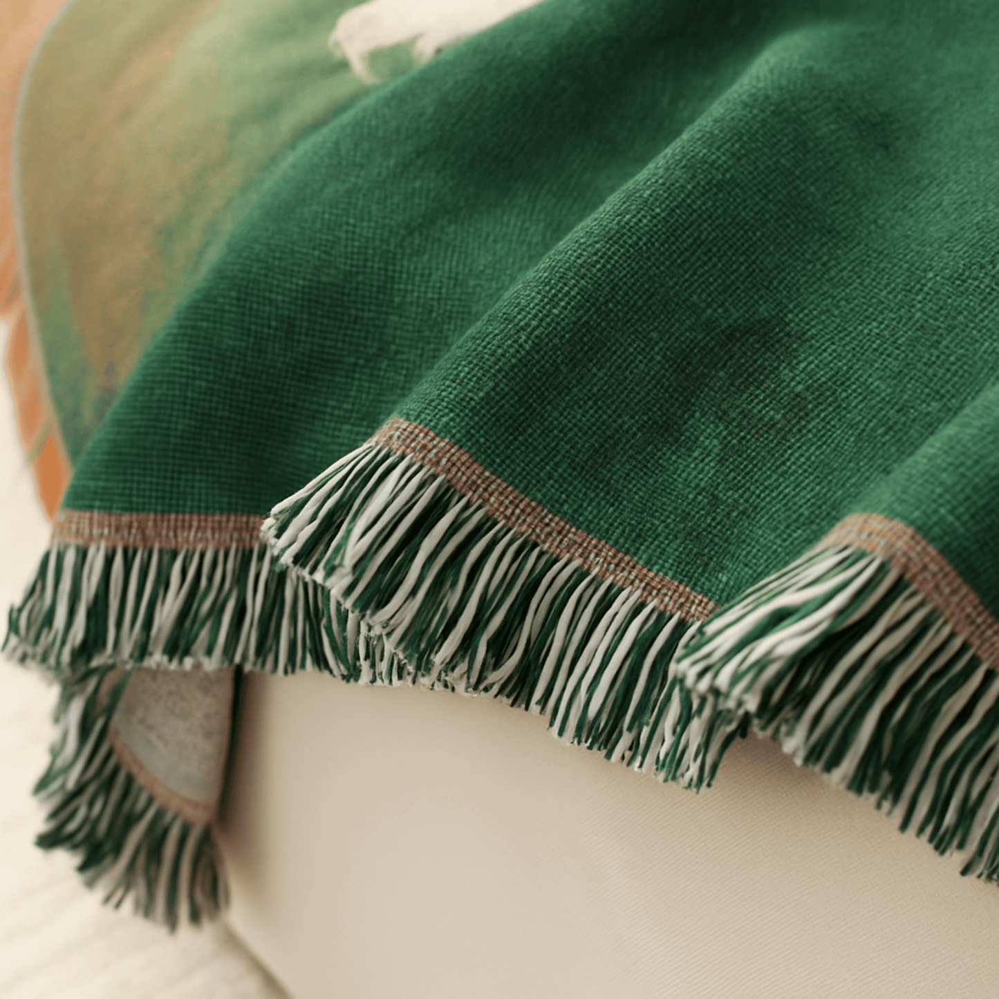 Green blanket with fringes draped over a surface