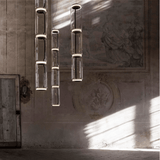 Modern chandelier hanging in a room with sunlight casting shadows on the wall.