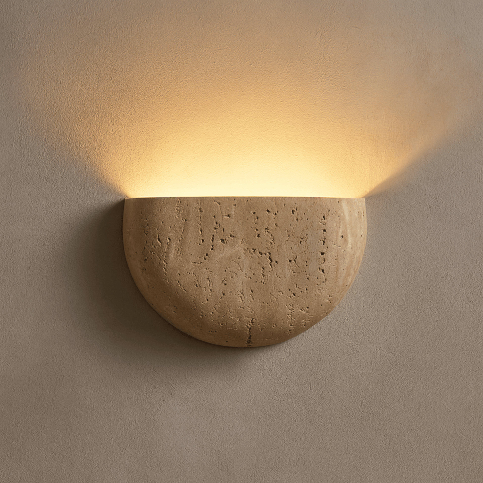 Ceramic wall sconce emitting warm light on a beige wall