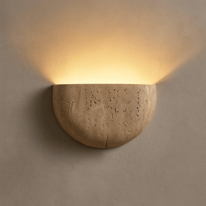 Ceramic wall sconce emitting warm light on a beige wall
