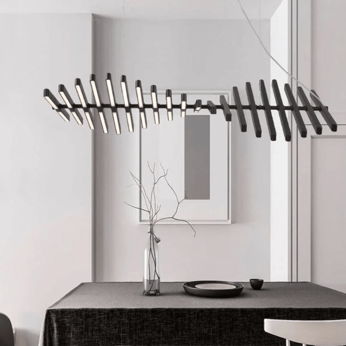 Modern chandelier hanging above a dining table with a minimalistic decor.