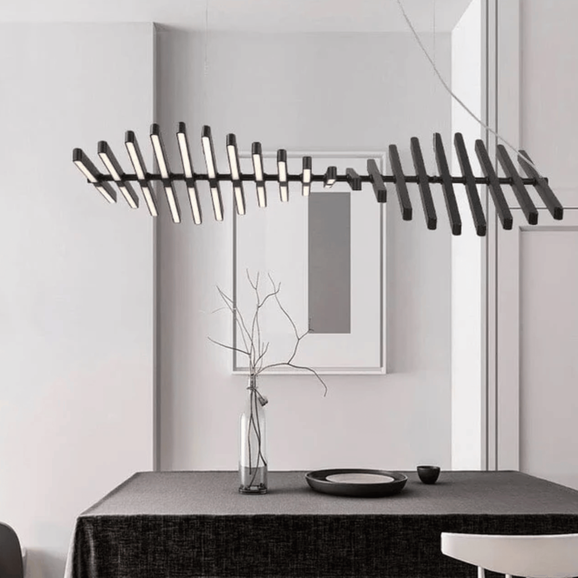 Modern chandelier hanging above a dining table with a minimalistic decor.